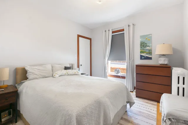 a bedroom with a bed and a lamp on dresser