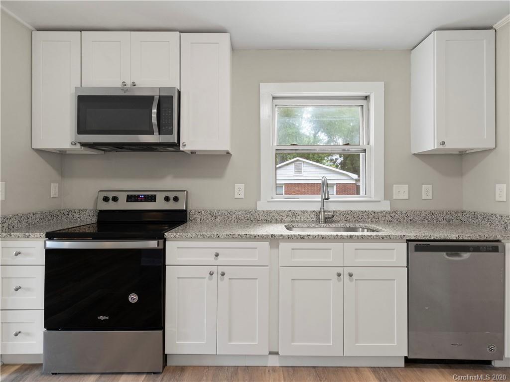 4152 Blenhein Road Charlotte, NC 28208 - Photo 21 of 34 a kitchen with stainless steel appliances granite countertop a stove a microwave and wooden cabinets