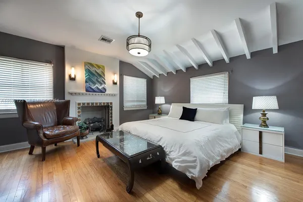 a spacious bedroom with a bed a chandelier and a fireplace