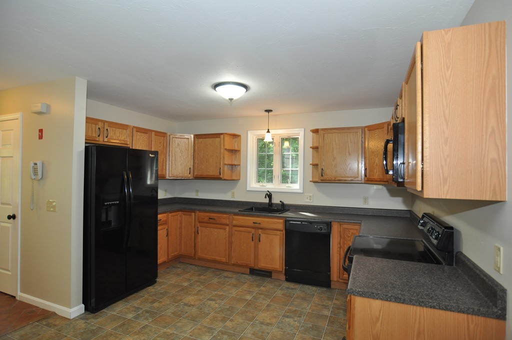 496 Loring Road Barre, MA 01005 - Photo 7 of 27 a kitchen with a sink a refrigerator and wooden cabinets