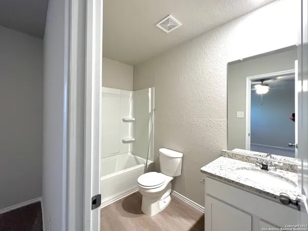 a bathroom with a granite countertop toilet a sink and a mirror