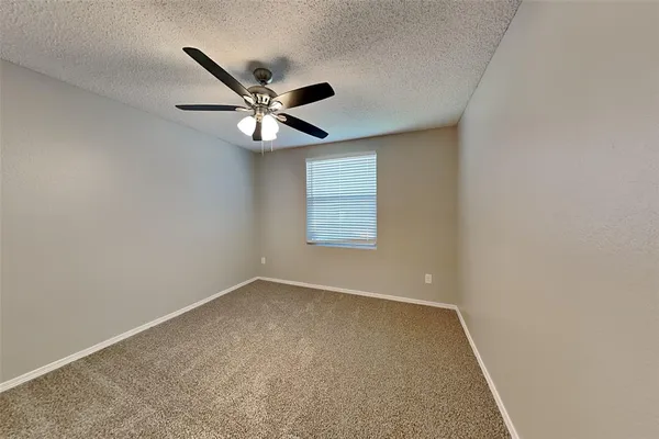 an empty room with a window and a fan
