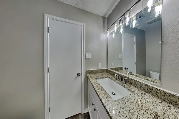 a bathroom with a granite countertop double vanity sink and mirror