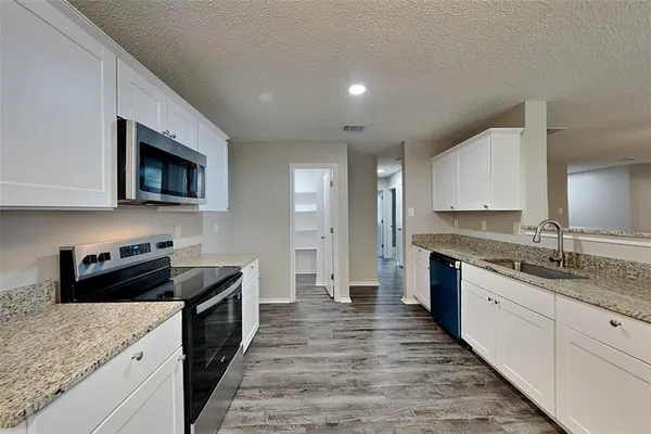 a kitchen with granite countertop kitchen island sink stove and cabinets
