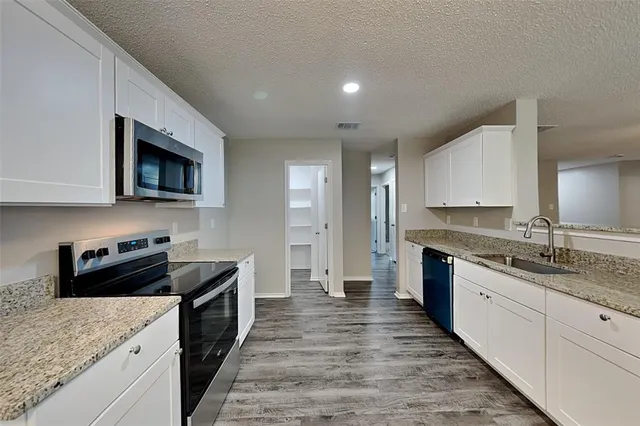 a kitchen with granite countertop kitchen island sink stove and cabinets
