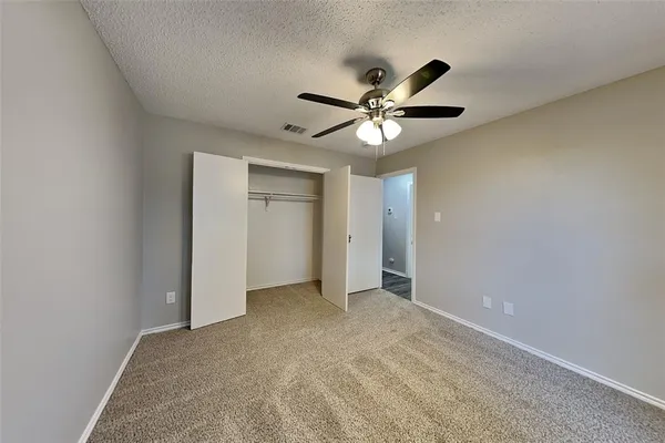 an empty room with closet and a ceiling fan