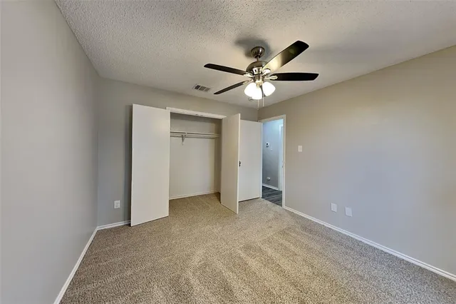 an empty room with closet and a ceiling fan