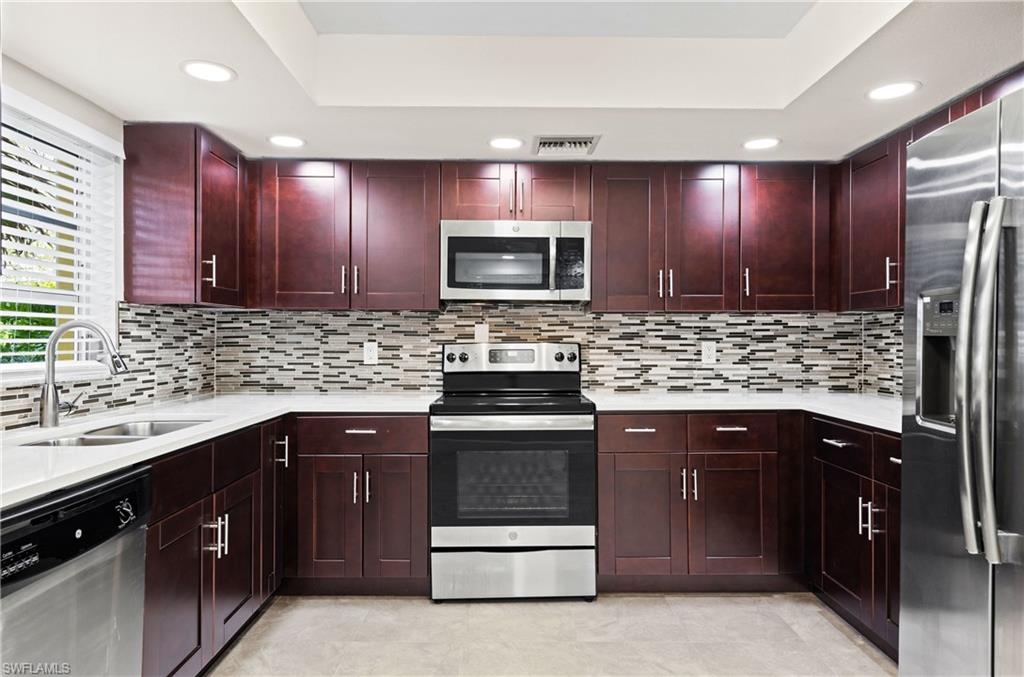 a kitchen with stainless steel appliances granite countertop wooden cabinets a stove top oven and sink