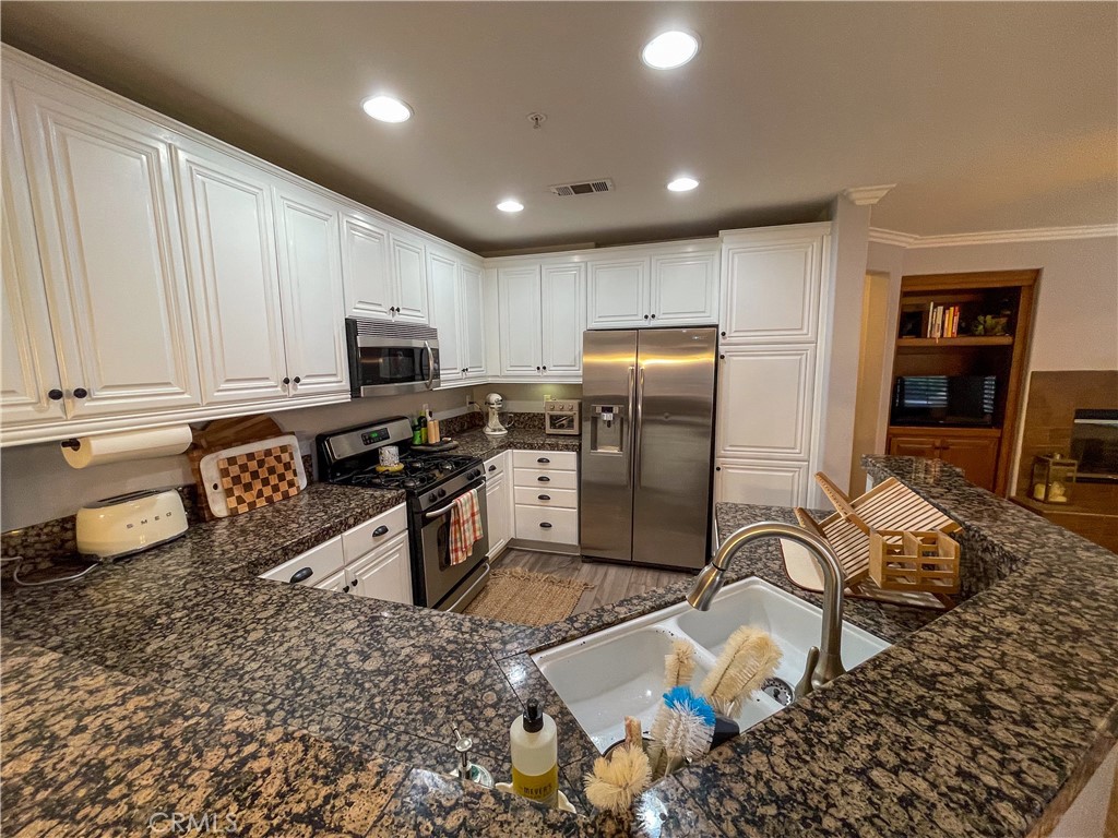 33570 Emerson Way, Unit C Temecula, CA 92592 - Photo 15 of 52 a kitchen with stainless steel appliances granite countertop a refrigerator a stove a sink a dining table and chairs