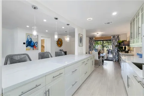 a large white kitchen with a large counter top furniture and a chandelier