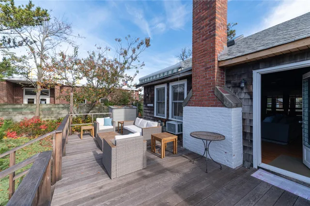 a view of a patio with couches table and chairs with wooden floor and fence