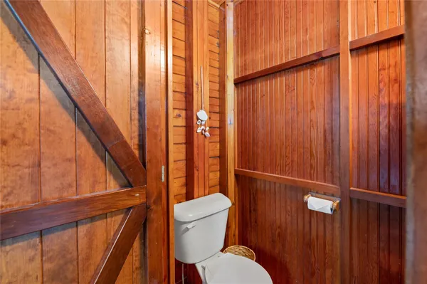 a bathroom with a toilet a sink and wooden floor