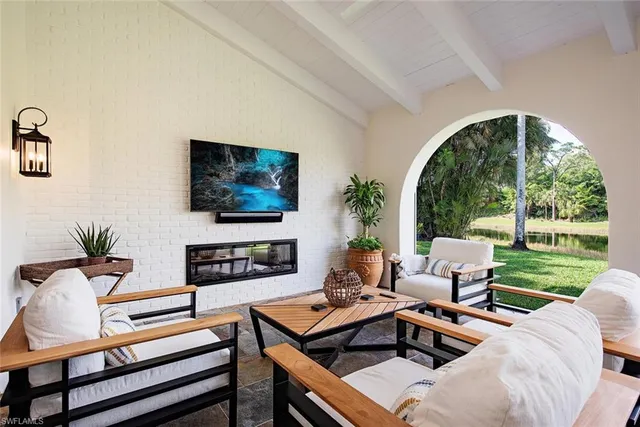 a living room with furniture a flat screen tv and a floor to ceiling window