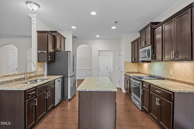 a large kitchen with stainless steel appliances granite countertop a stove a sink and a microwave