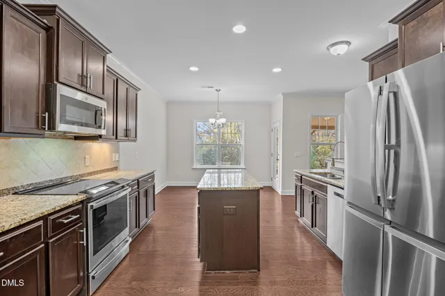 a kitchen with stainless steel appliances granite countertop a refrigerator a stove a sink and a microwave