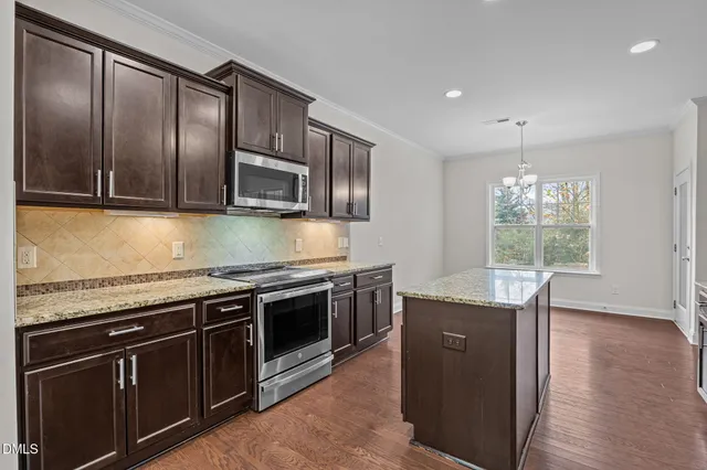a kitchen with stainless steel appliances granite countertop wooden cabinets and a stove top oven