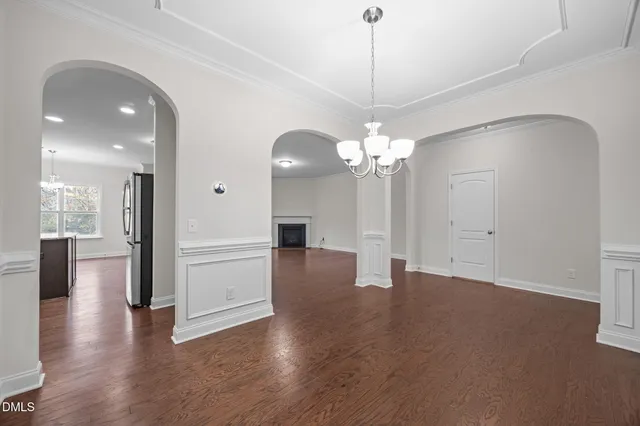 a view of a livingroom with a chandelier fan wooden floor and windows