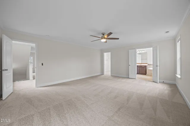 a view of an empty room with a chandelier fan and a window