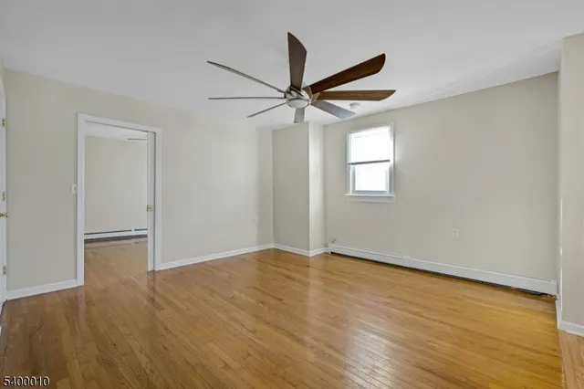 an empty room with wooden floor ceiling fan and windows