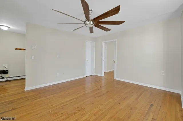 an empty room with wooden floor and a ceiling fan