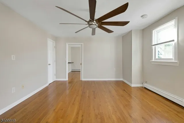 an empty room with wooden floor fan and windows