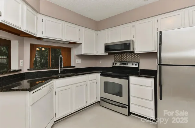 a kitchen with granite countertop white cabinets and stainless steel appliances
