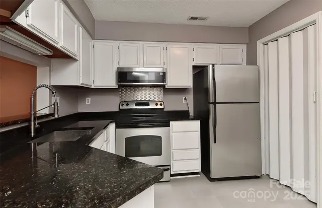 a kitchen with a stove a refrigerator and cabinets