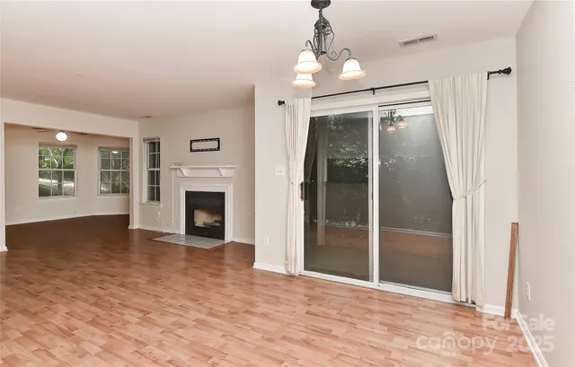 an empty room with windows fireplace and wooden floor