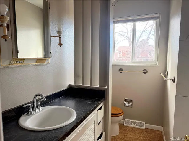 a bathroom with a granite countertop sink toilet and a mirror