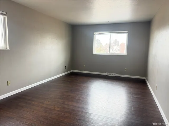 an empty room with wooden floor and windows