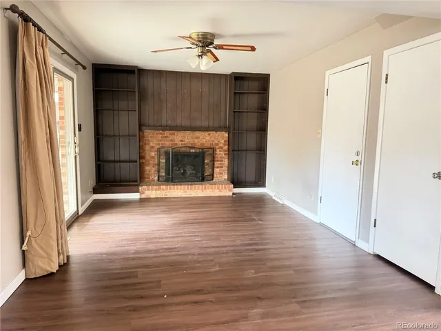 an empty room with wooden floor fireplace and windows