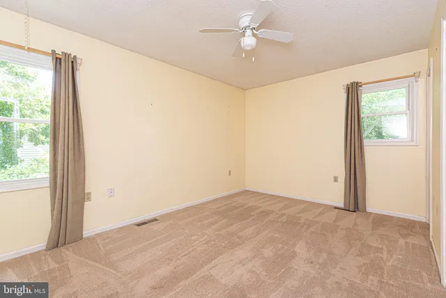 an empty room with a window and a fan