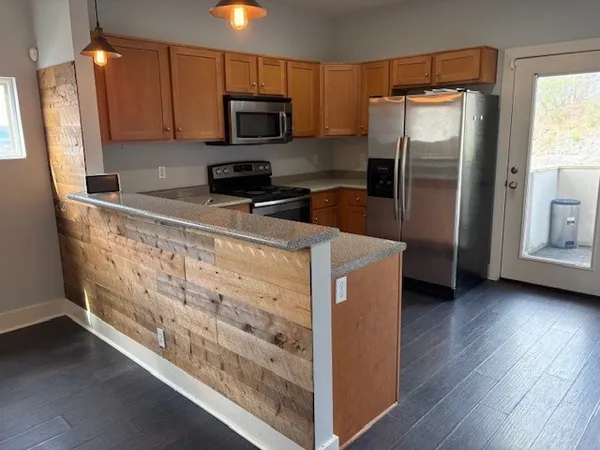 a kitchen with granite countertop a refrigerator a sink a stove a microwave and wooden floor