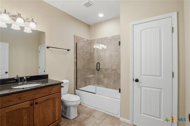 a bathroom with a granite countertop sink a toilet and shower