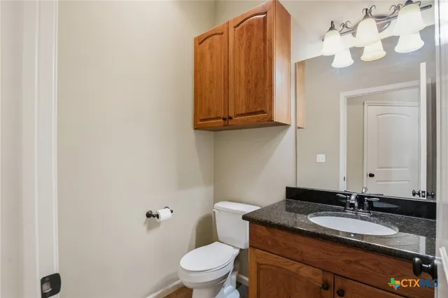 a bathroom with a granite countertop sink vanity mirror and toilet