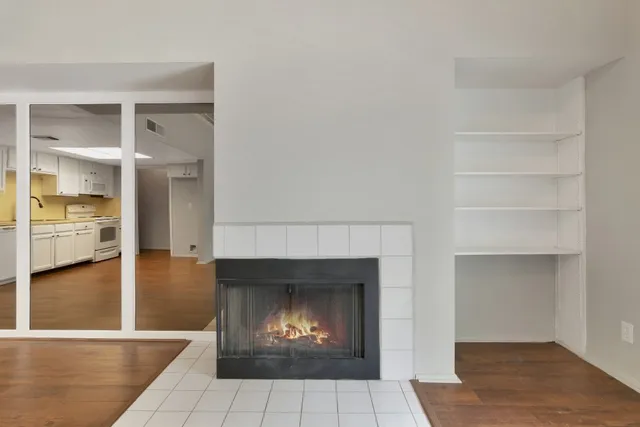 a room with a fireplace and a view of kitchen