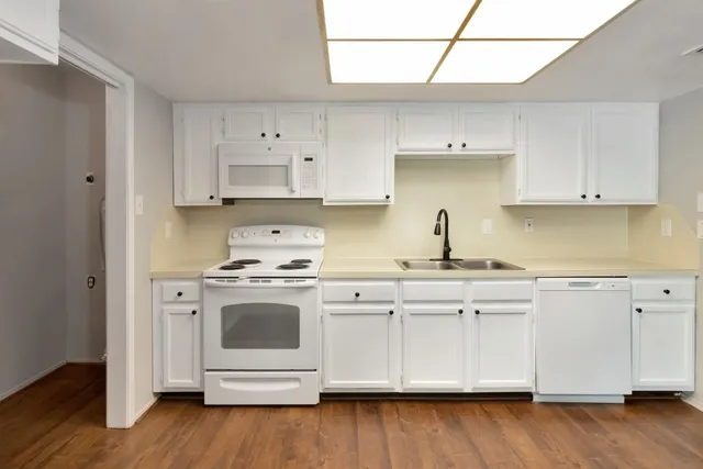 a white kitchen with granite countertop white cabinets and white appliances