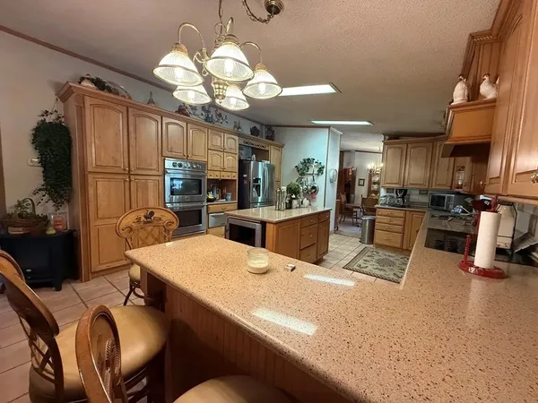 a kitchen with stainless steel appliances kitchen island granite countertop a refrigerator a stove top oven a sink dishwasher and dining table with wooden floor