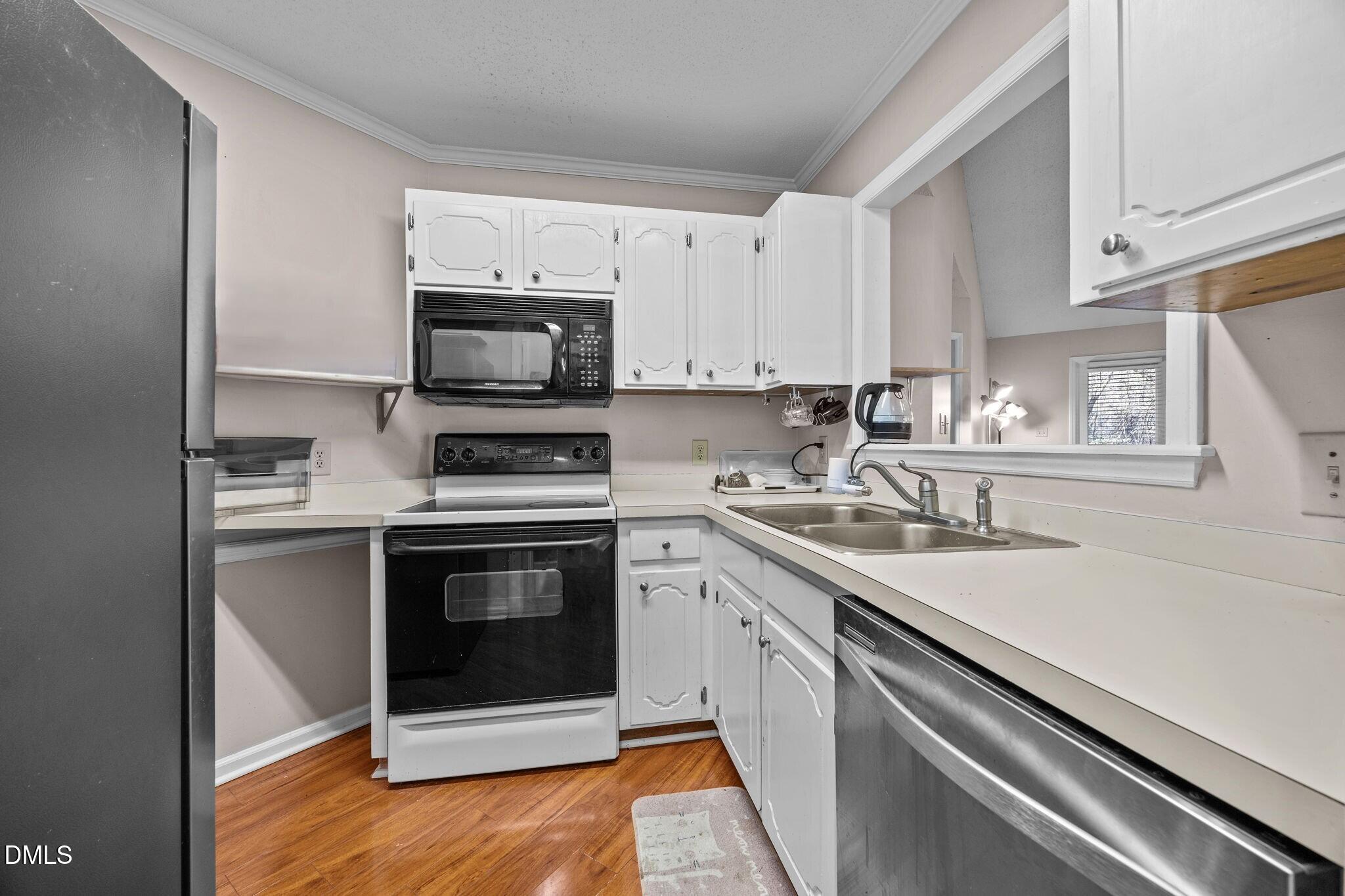 135 Boldleaf Court Cary, NC 27513 - Photo 5 of 27 a kitchen with granite countertop a stove a sink and a microwave