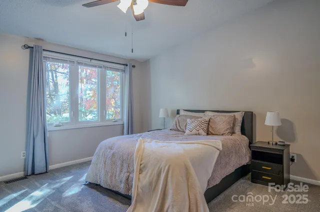 a bedroom with a bed lamp and a large window