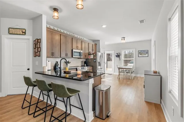 a kitchen with stainless steel appliances kitchen island granite countertop a table and chairs in it
