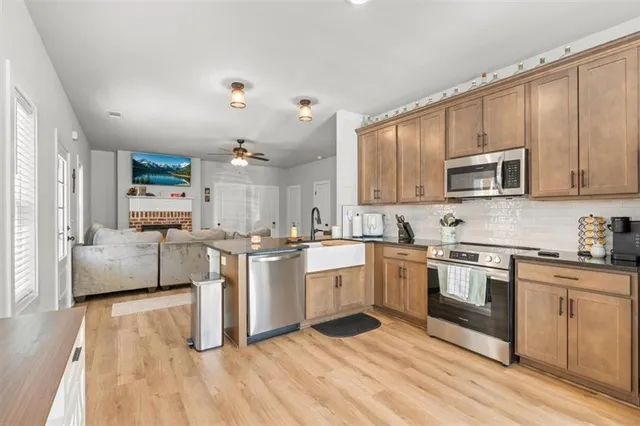 a kitchen with stainless steel appliances granite countertop a stove top oven a sink dishwasher and a refrigerator with wooden floor