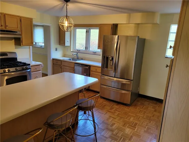 a kitchen with stainless steel appliances a refrigerator a stove a sink a dining table and chairs