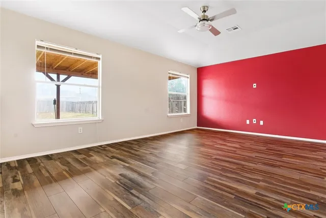 a view of an empty room with window and wooden floor