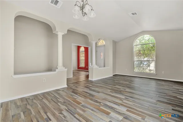 a view of an empty room with wooden floor and a window