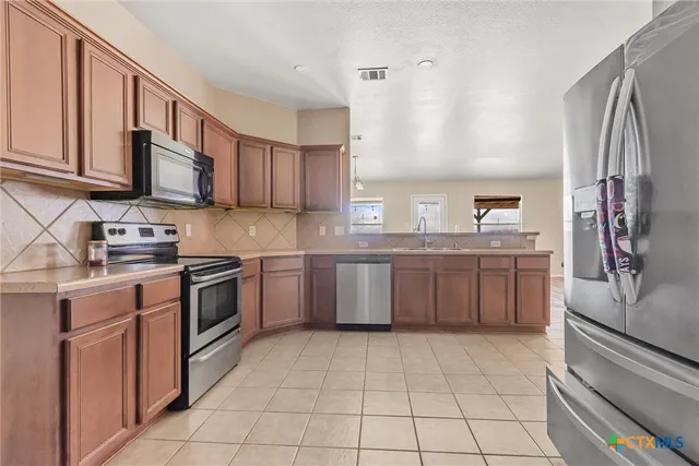 a kitchen with stainless steel appliances granite countertop a stove top oven a sink dishwasher and a refrigerator