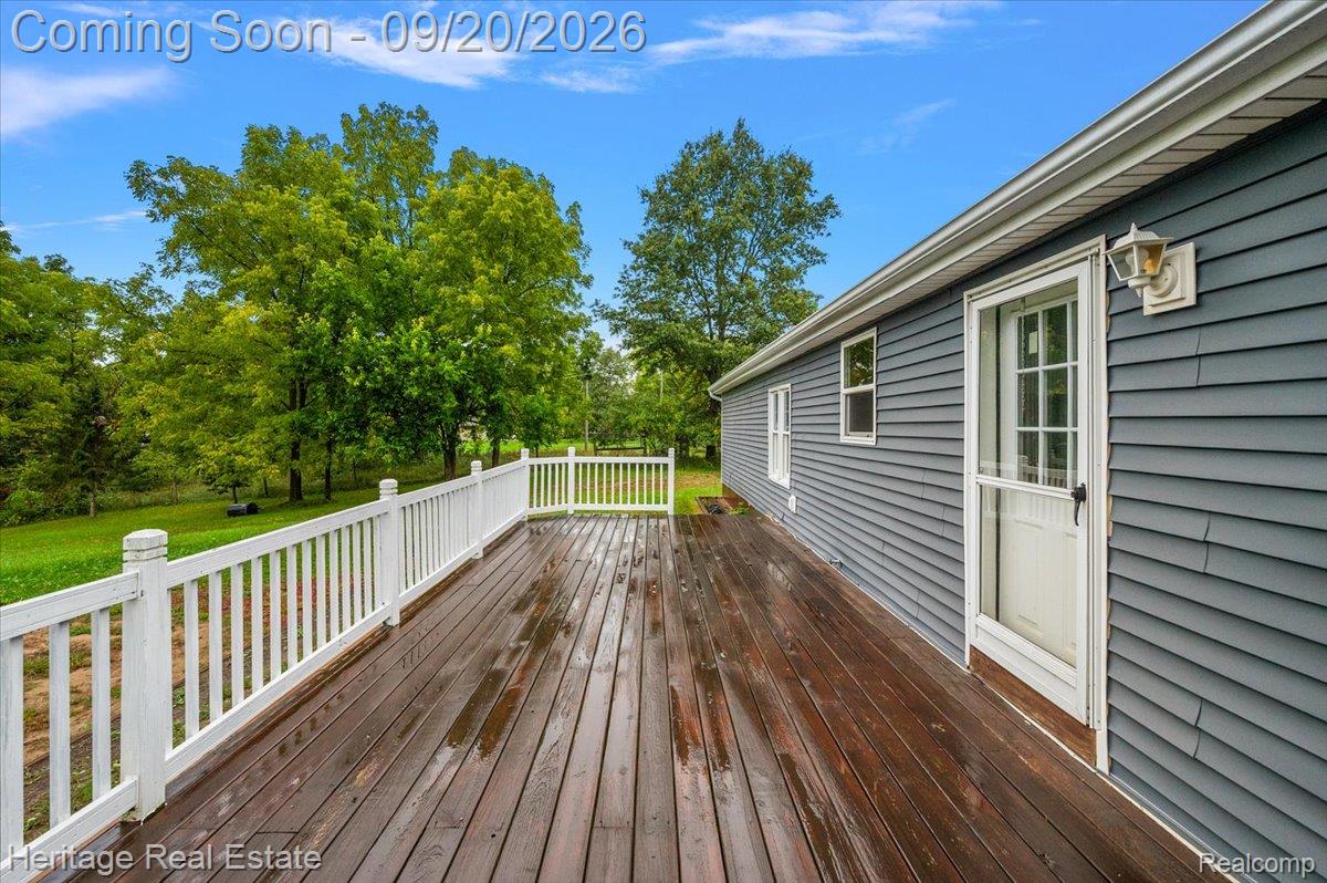 3337 Le Valley Road Columbiaville, MI 48421 - Photo 7 of 57 Expansive wood-finish deck with white railings, a screen door, and exterior wall lantern