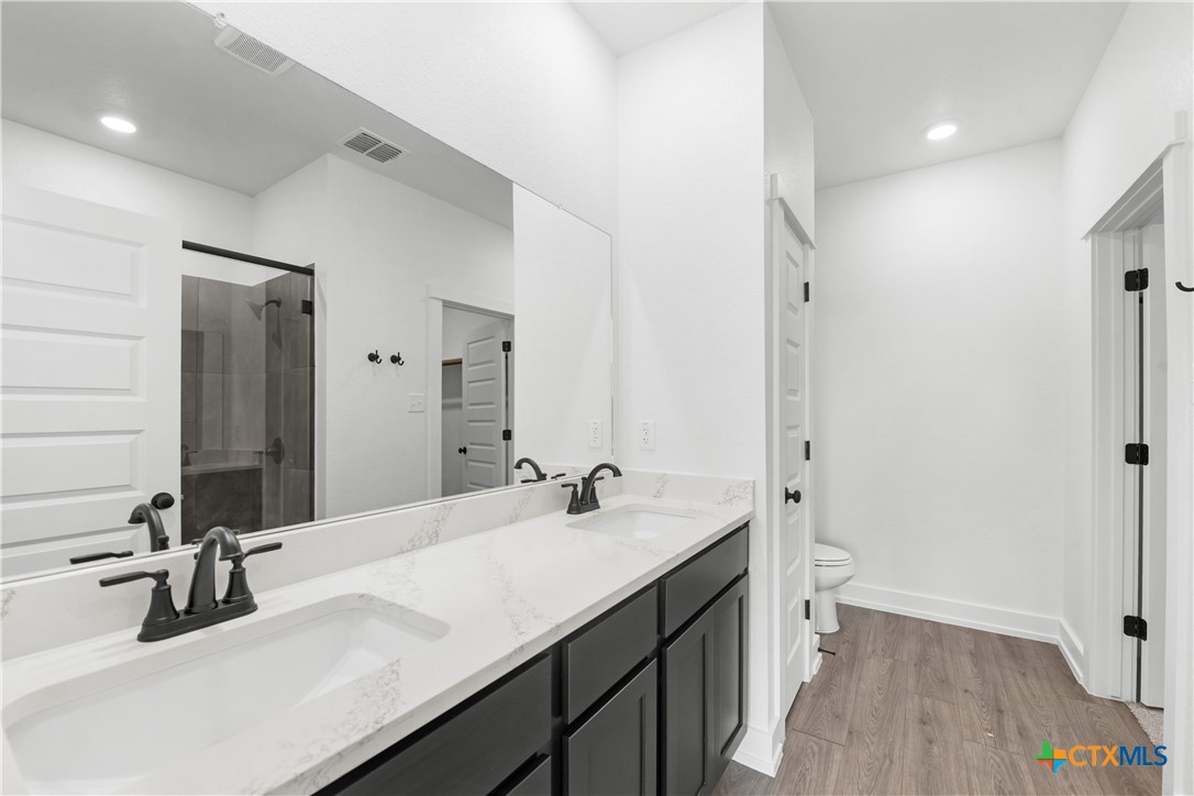 1807 Bear Grass Rdg Road Temple, TX 76501 - Photo 6 of 16 a bathroom with a double vanity sink a mirror and a bathtub