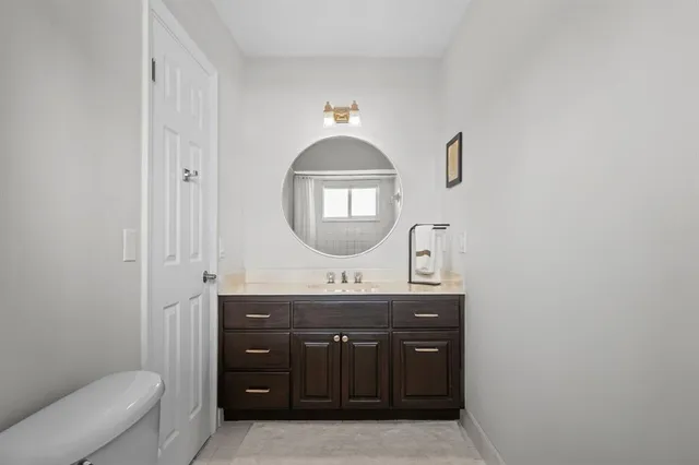 a bathroom with a granite countertop sink a mirror and toilet