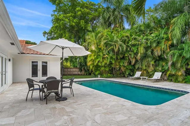 a view of a swimming pool with lawn chairs under an umbrella